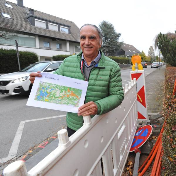 Reiner Pliefke steht mit Karte zum Novanetz-Ausbau an einer Baustelle mit orangenen Glasfaser-Kabeln.