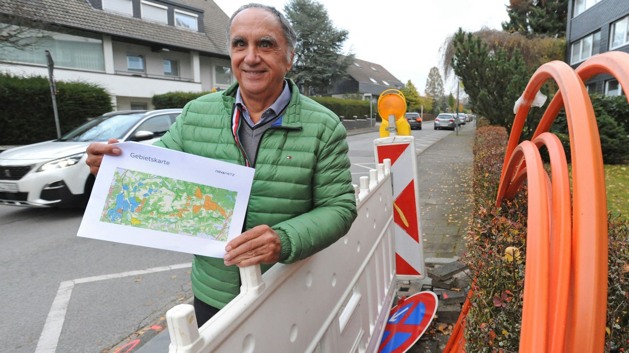 Reiner Pliefke steht mit Karte zum Novanetz-Ausbau an einer Baustelle mit orangenen Glasfaser-Kabeln.