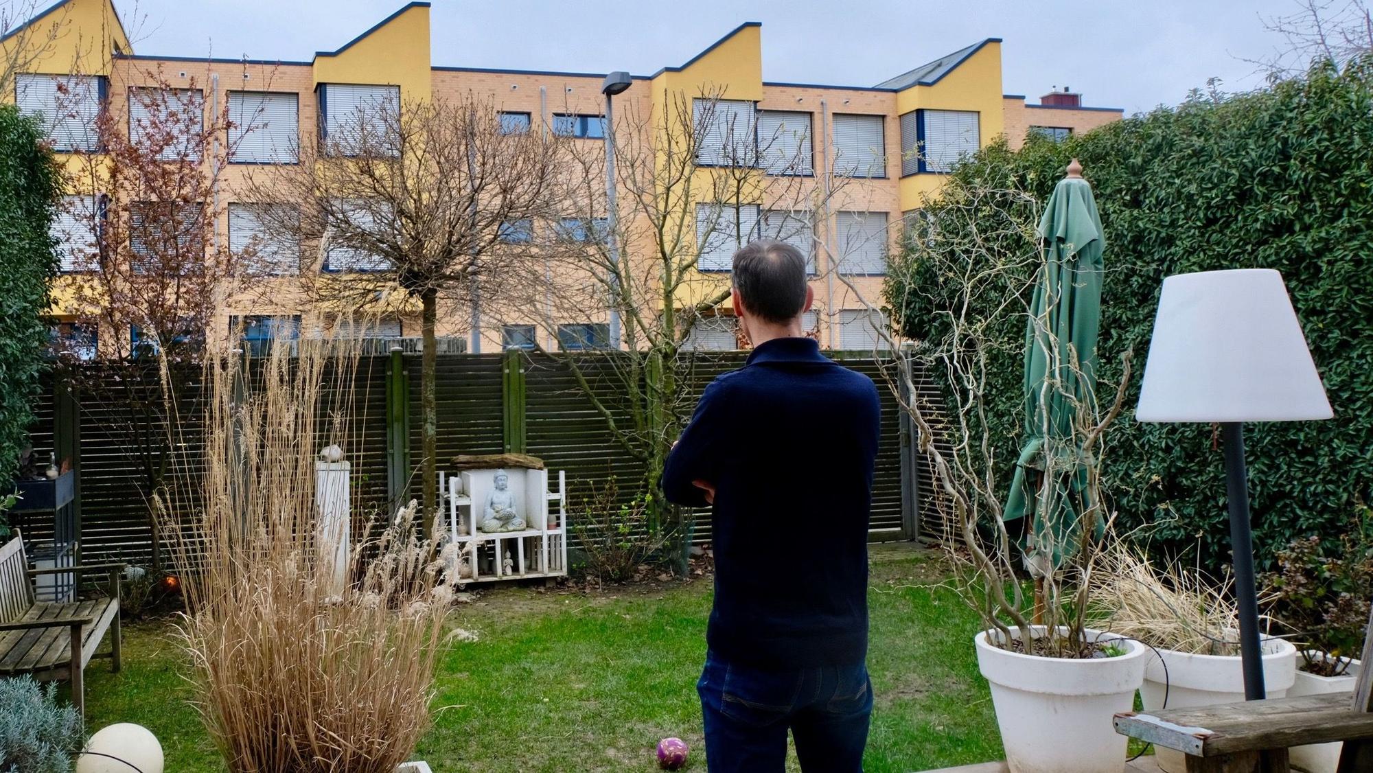Anwohner, der von seinem Garten aus auf ein Schulgebäude blickt
