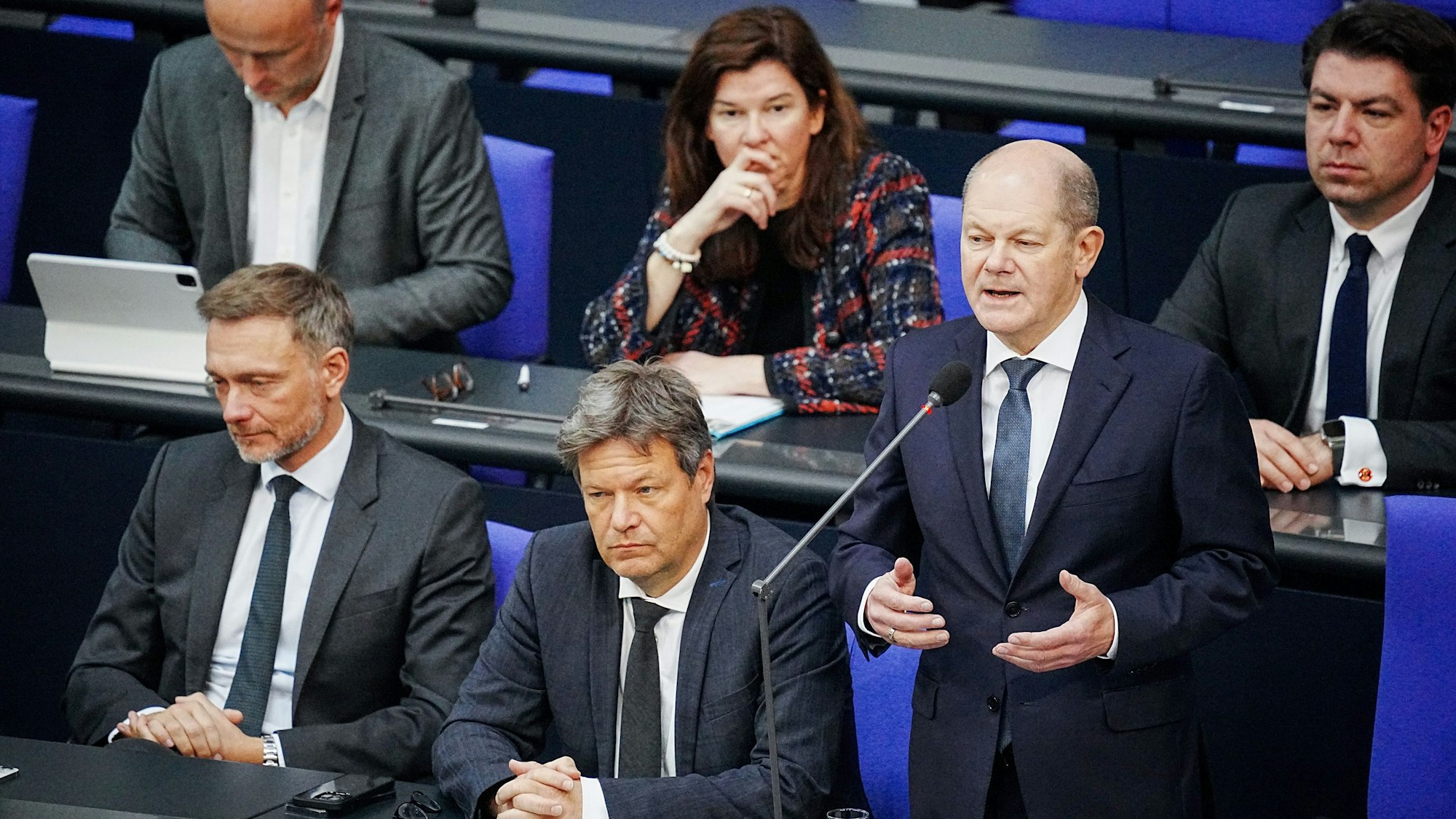 Bundeskanzler Olaf Scholz (SPD, 2.v.r) spricht im Bundestag bei der Befragung der Bundesregierung neben Christian Lindner (FDP, l), Bundesminister der Finanzen, und Robert Habeck (Bündnis 90/Die Grünen, M), Bundesminister für Wirtschaft und Klimaschutz, zu den Abgeordneten im Plenum.