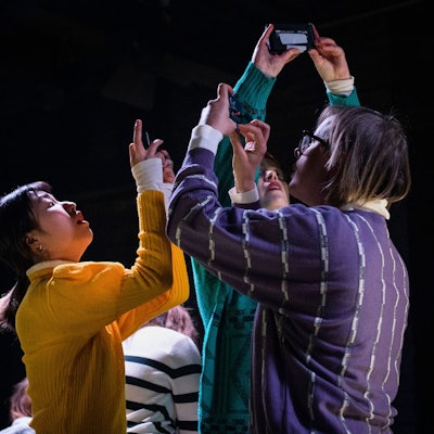 Die Schauspielerinnen und Schauspieler stehen dicht beieinander und haben ihre Handys erhoben, um Fotos zu machen.