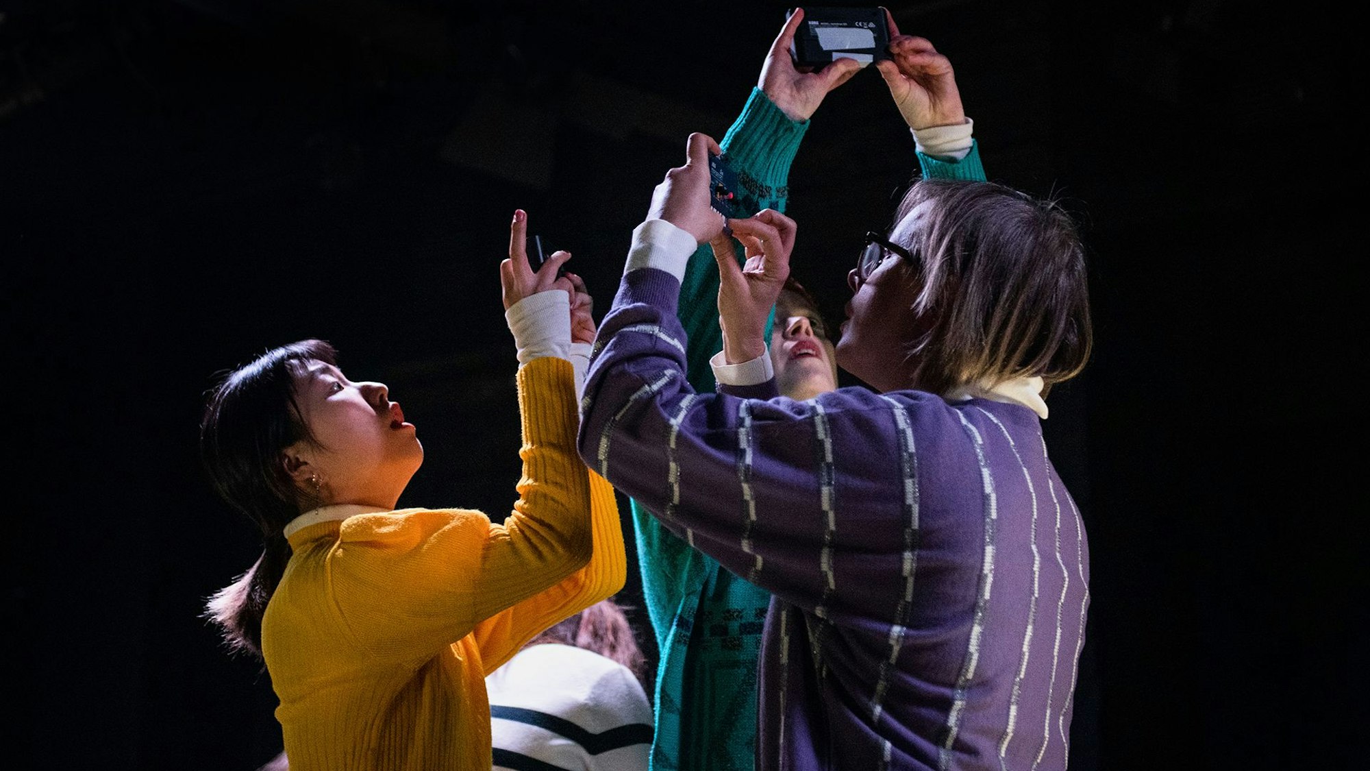 Die Schauspielerinnen und Schauspieler stehen dicht beieinander und haben ihre Handys erhoben, um Fotos zu machen.