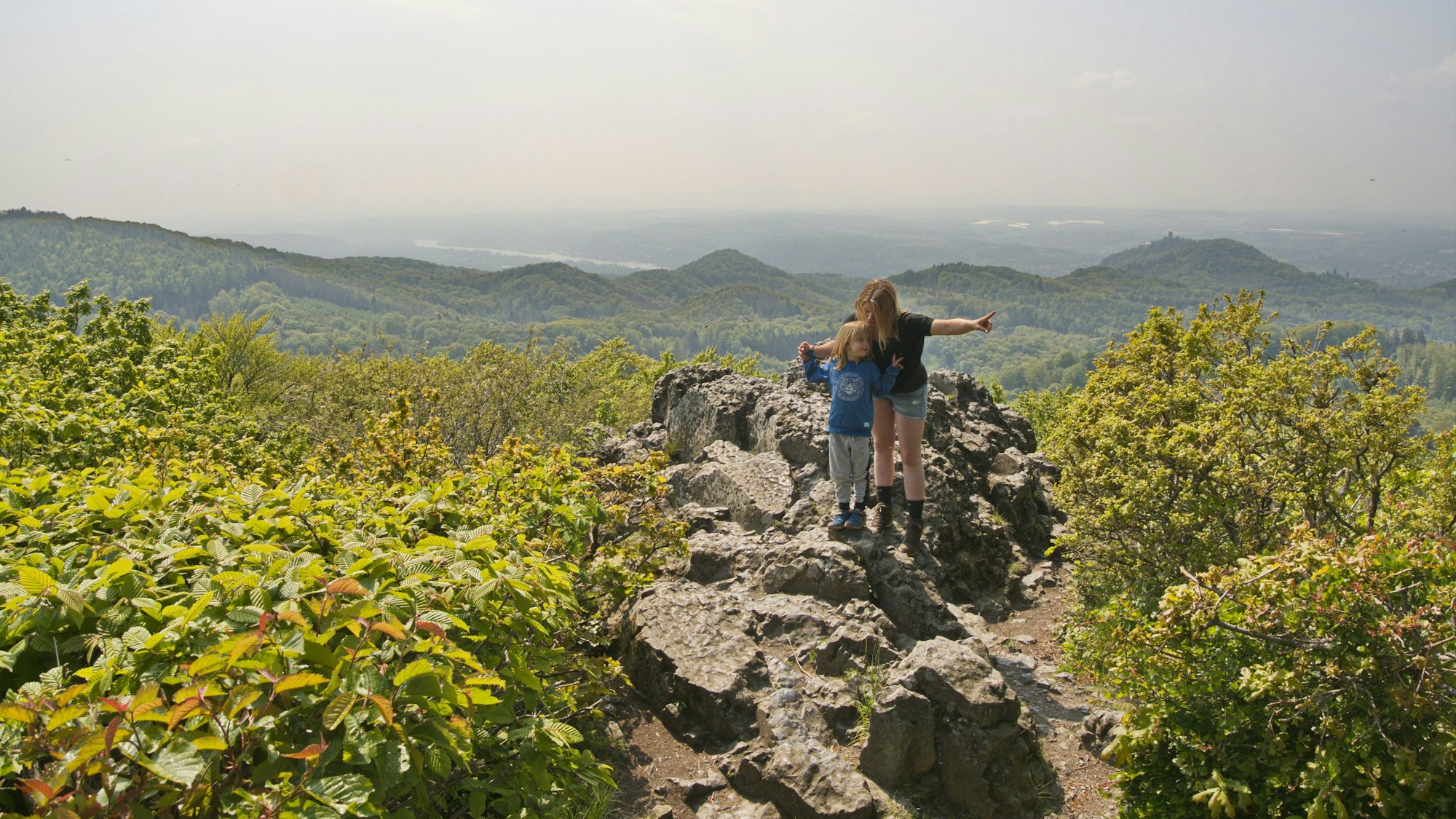 Eine Mutter und ihr Kind stehen auf den Felsen des Oelbergs im Siebengebirge.