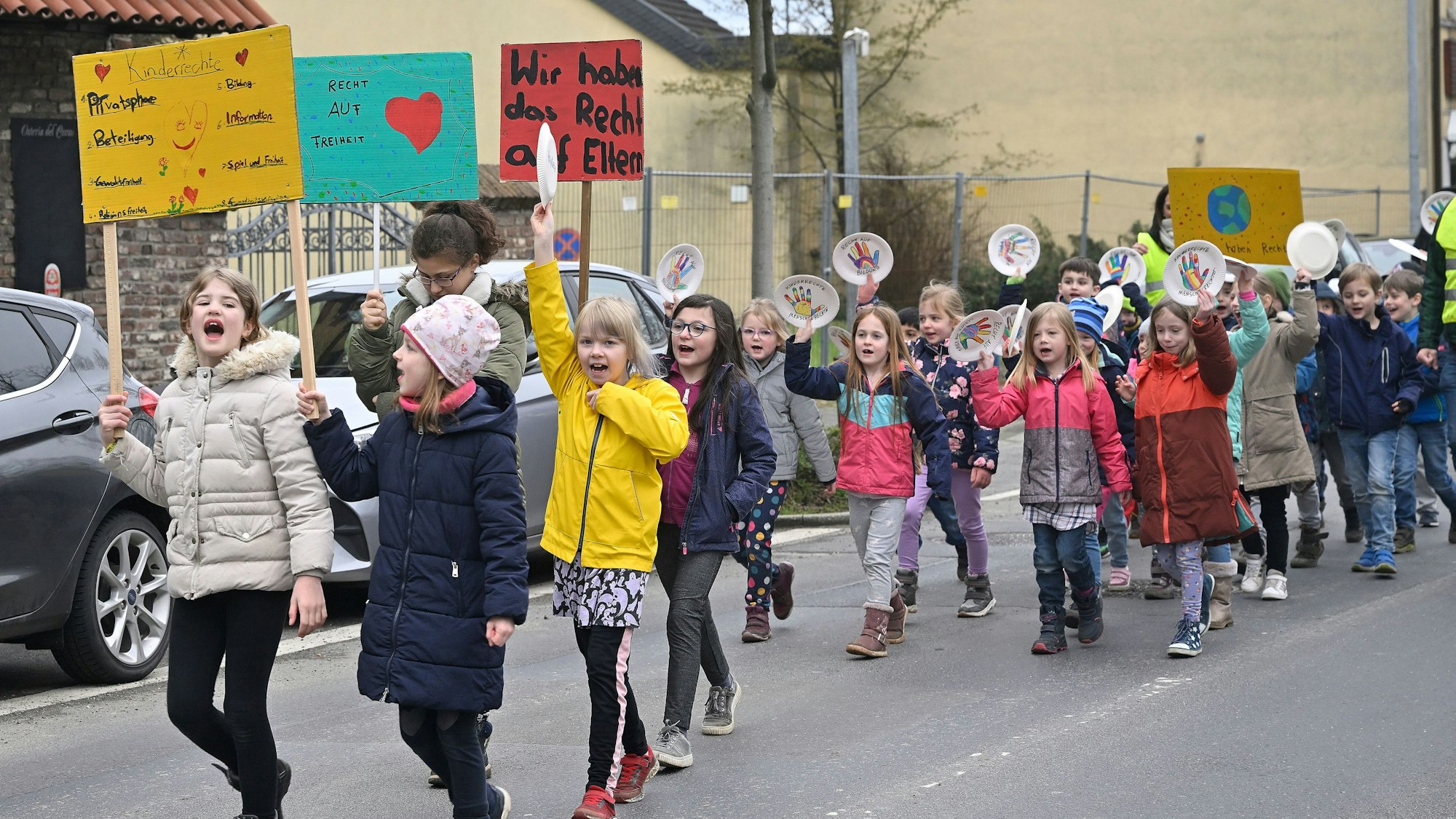 Kinder laufen in einem Demozug und halten Plakate hoch.