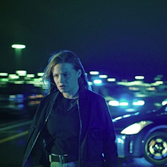 Jasna Fritzi Bauer in der Rolle Liv Moormann im Bremer „Tatort“ „Donuts“. Sie geht nachts von einem Auto weg und schaut düster. Hinter ihr leuchten diverse Lampen sowie die Scheinwerfer des blauen Sportwagens.