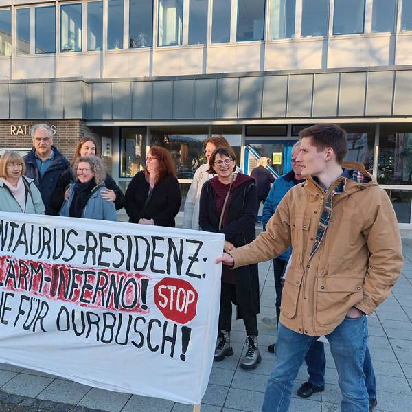 Einige Personen demonstrieren vor dem Rathaus. Sie halten ein Banner, auf dem steht: „Centaurus-Residenz: Lärm-Inferno! Ruhe für Durbusch!“