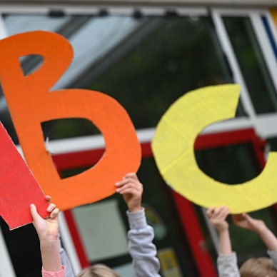 Grundschüler halten die Buchstaben A, B,C hoch.