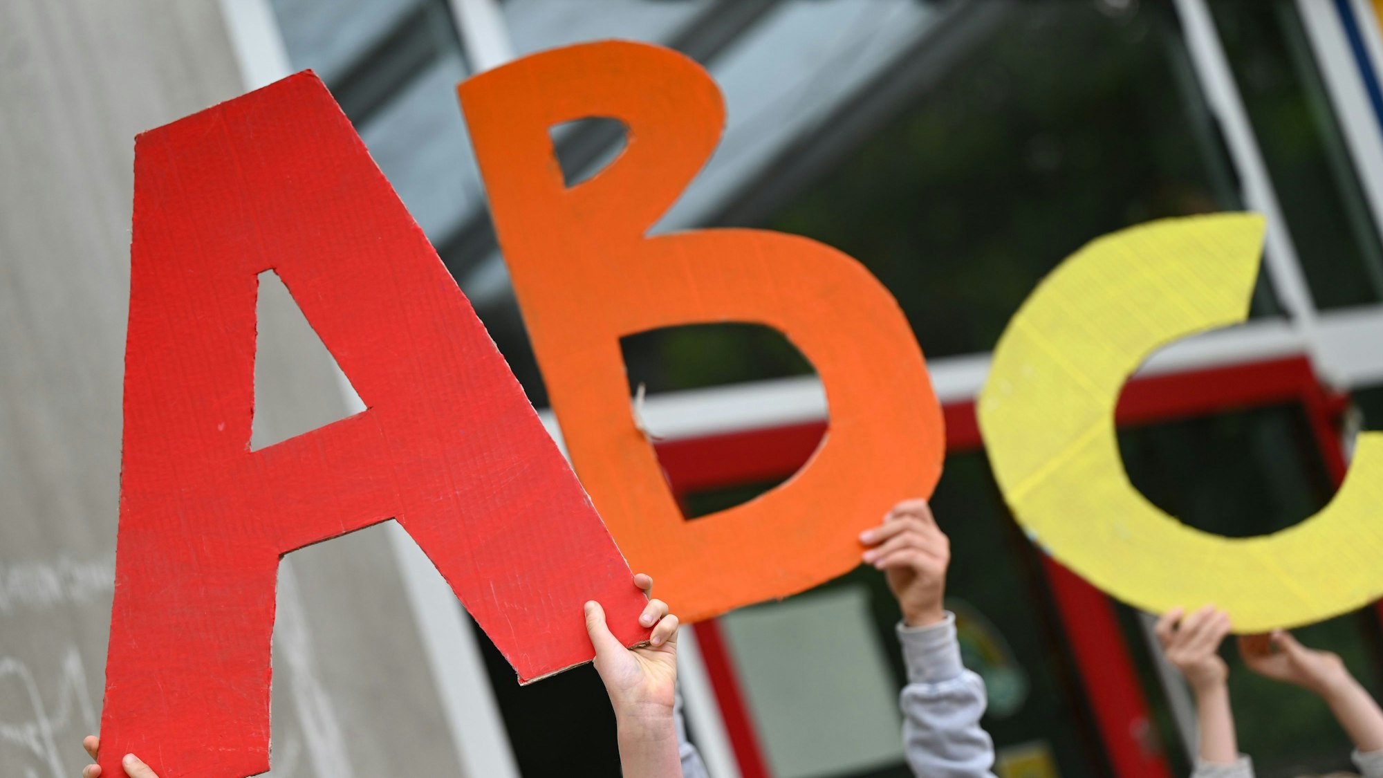 Grundschüler halten die Buchstaben A, B,C hoch.
