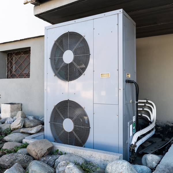 Die Lüftungsanlage einer Wärmepumpe steht vor einem Wohnhaus.