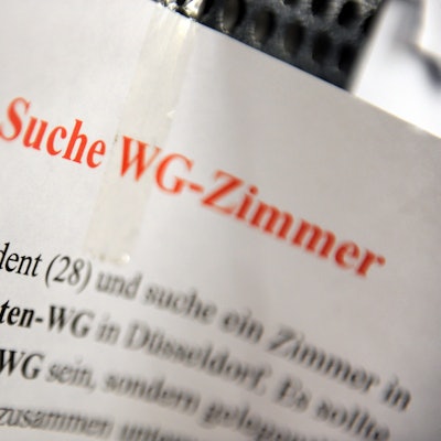 Ein Zettel mit der Aufschrift „Suche WG-Zimmer“ hängt an einem Schwarzen Brett.