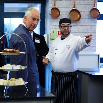 König Charles III. (M) bei einem Besuch der Londoner Gemeinschaftsküche, um Studenten und Freiwillige zu treffen und die Einrichtungen zu besichtigen. Unter anderem besuchte er den Markt für überschüssige Lebensmittel, die Kochschule und das «Kind Cafe». +++ dpa-Bildfunk +++