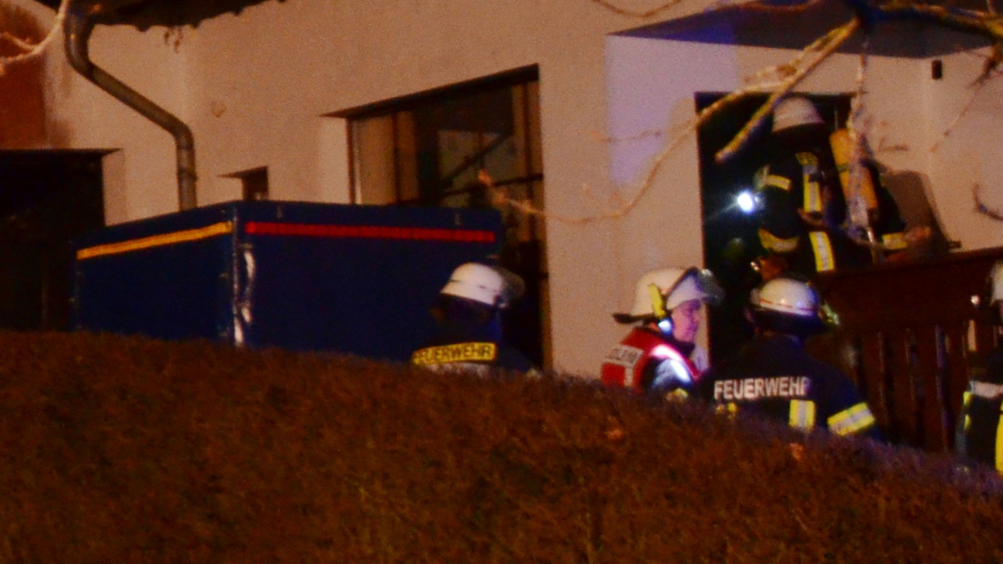 Man sieht Einsatzkräfte unter Atemschutz, die in das Wohnhaus eindringen.