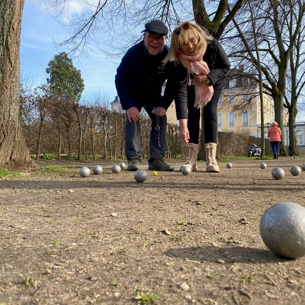 Zwei Menschen spielen Boule in einem Park.
