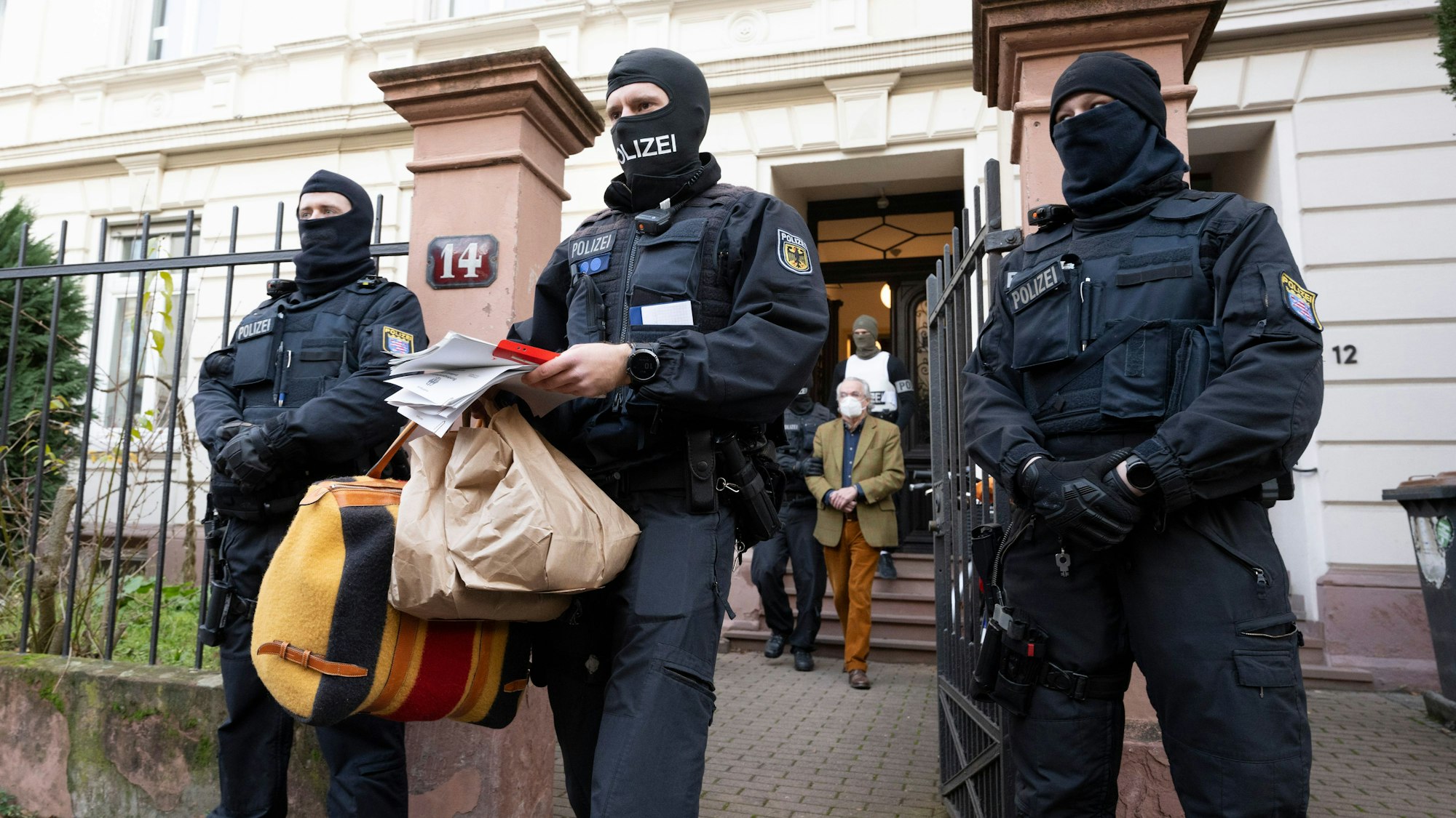 Bei einer Razzia gegen sogenannte «Reichsbürger» führen vermummte Polizisten, nach der Durchsuchung eines Hauses Heinrich XIII Prinz Reuß (hinten, Mitte) zu einem Polizeifahrzeug. Ein Polizist trägt dabei, Tüten, eine Tasche und Papiere.