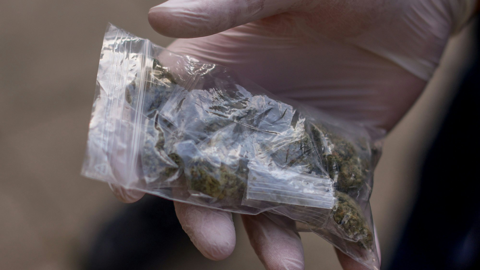 Ein Polizist zeigt eine sichergestellte Tüte Haschisch während einer Razzia der Polizei gegen Drogendealer am Ebertplatz in Köln.