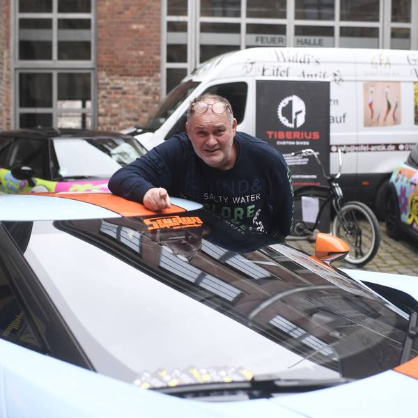 80-Euro-Waldi (Walter Lehnertz) steht an einem Sportwagen vor seiner neuen Galerie in Euskirchen.