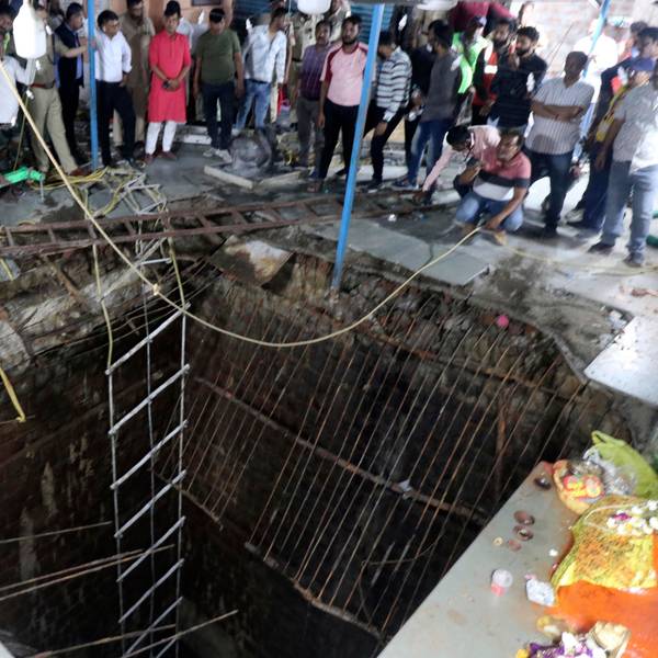 Indien, Indore: Menschen stehen neben einem alten Brunnenbauwerk, über das ein Tempelboden gebaut wurde, der eingebrochen ist.