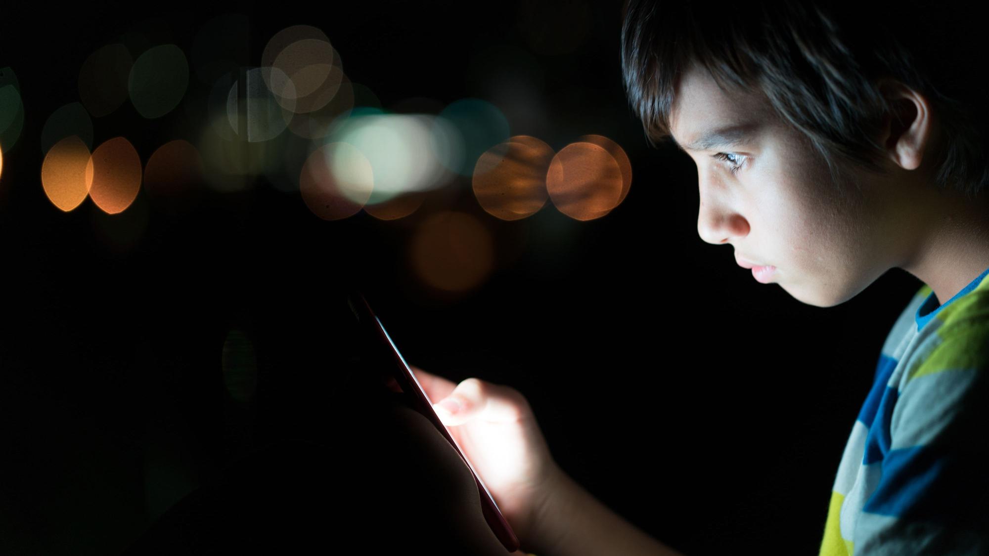 Kind schaut erschrocken auf ein Handy
