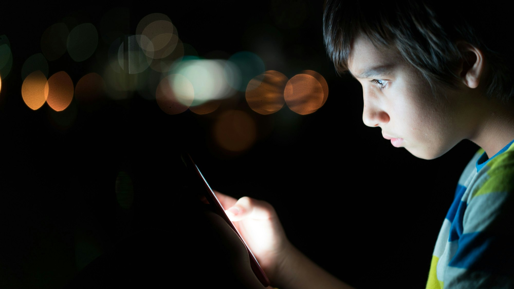 Kind schaut erschrocken auf ein Handy