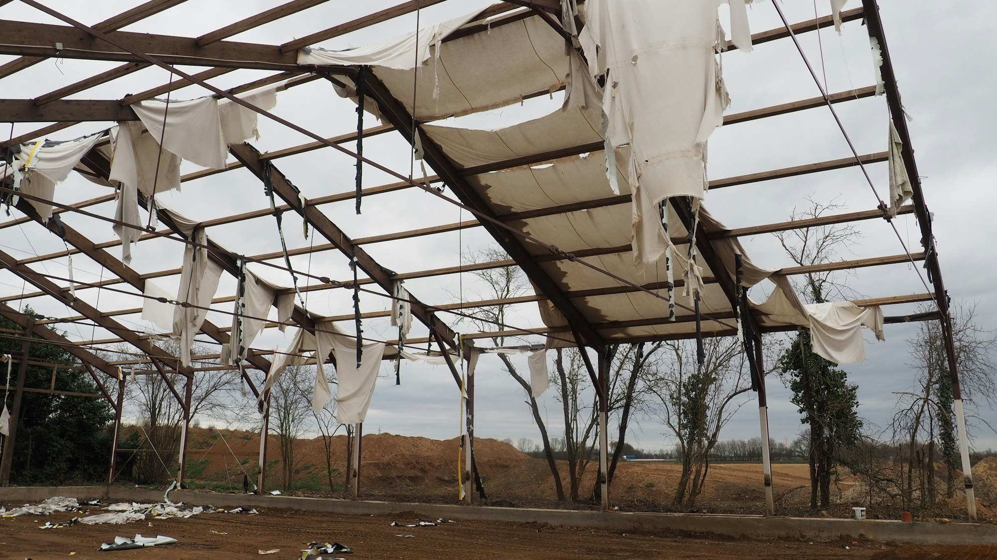 Das Gerüst der Reithalle steht noch auf dem Boden. Planen hängen in Fetzen vom Dach herab.