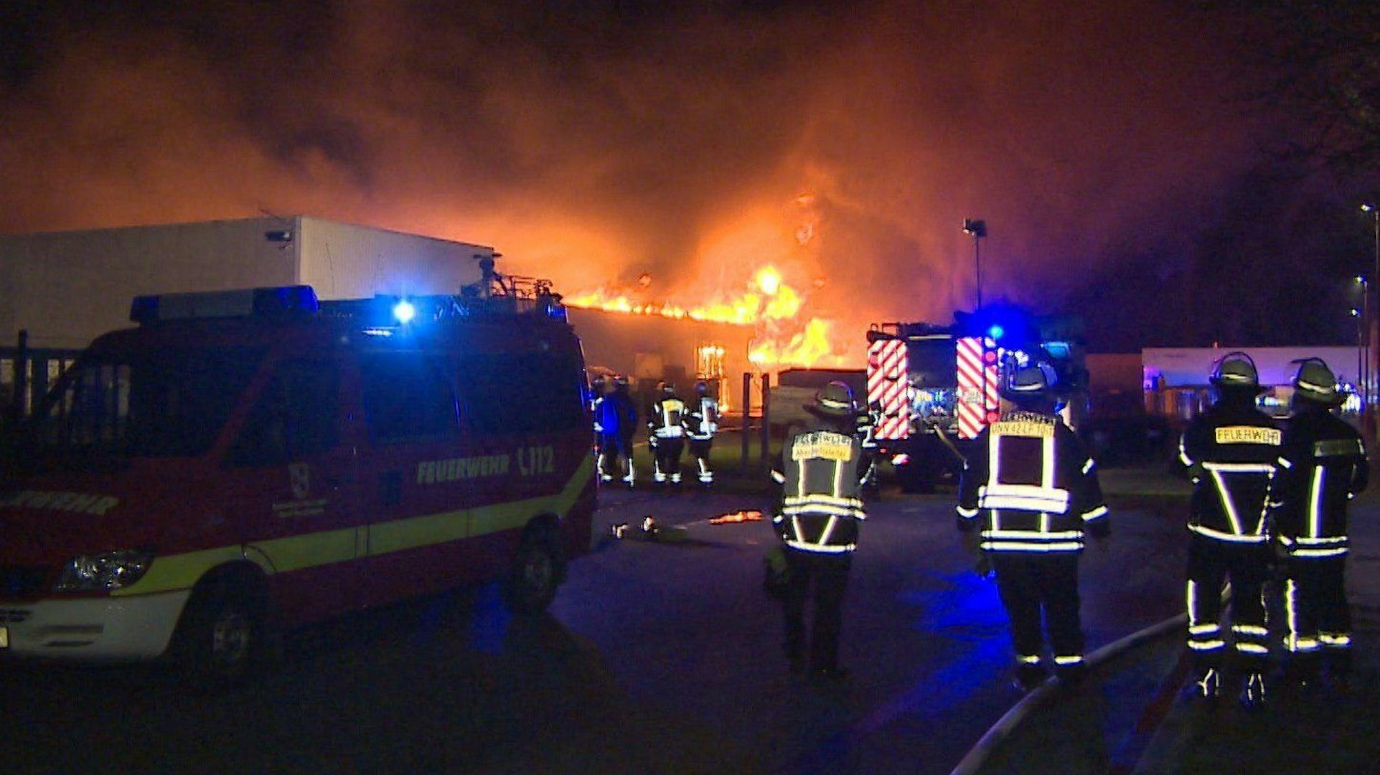Unna: Einsatzkräfte der Feuerwehr stehen an einem brennenden Firmengebäude