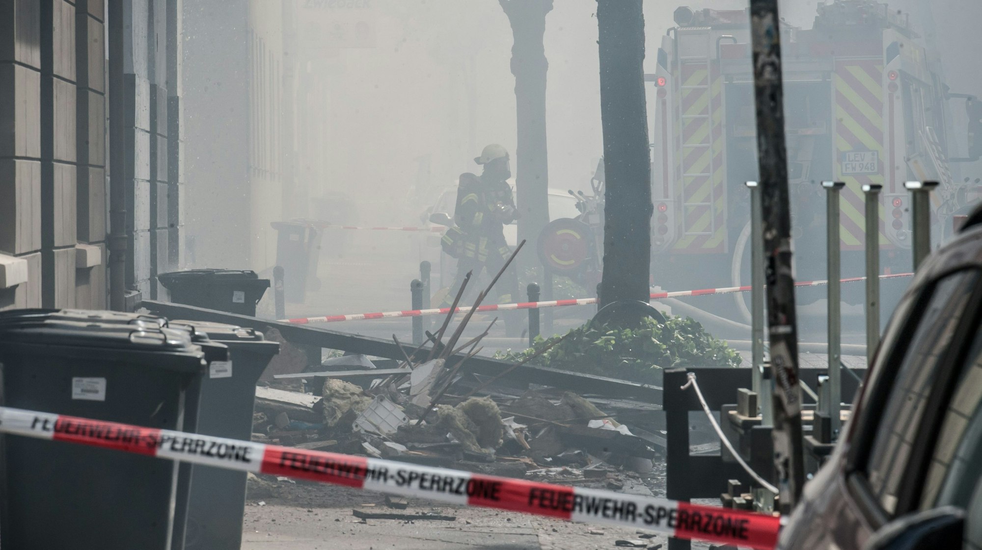 Trümmer liegen nach der Explosion auf der verrauchten Augustastraße in Opladen.