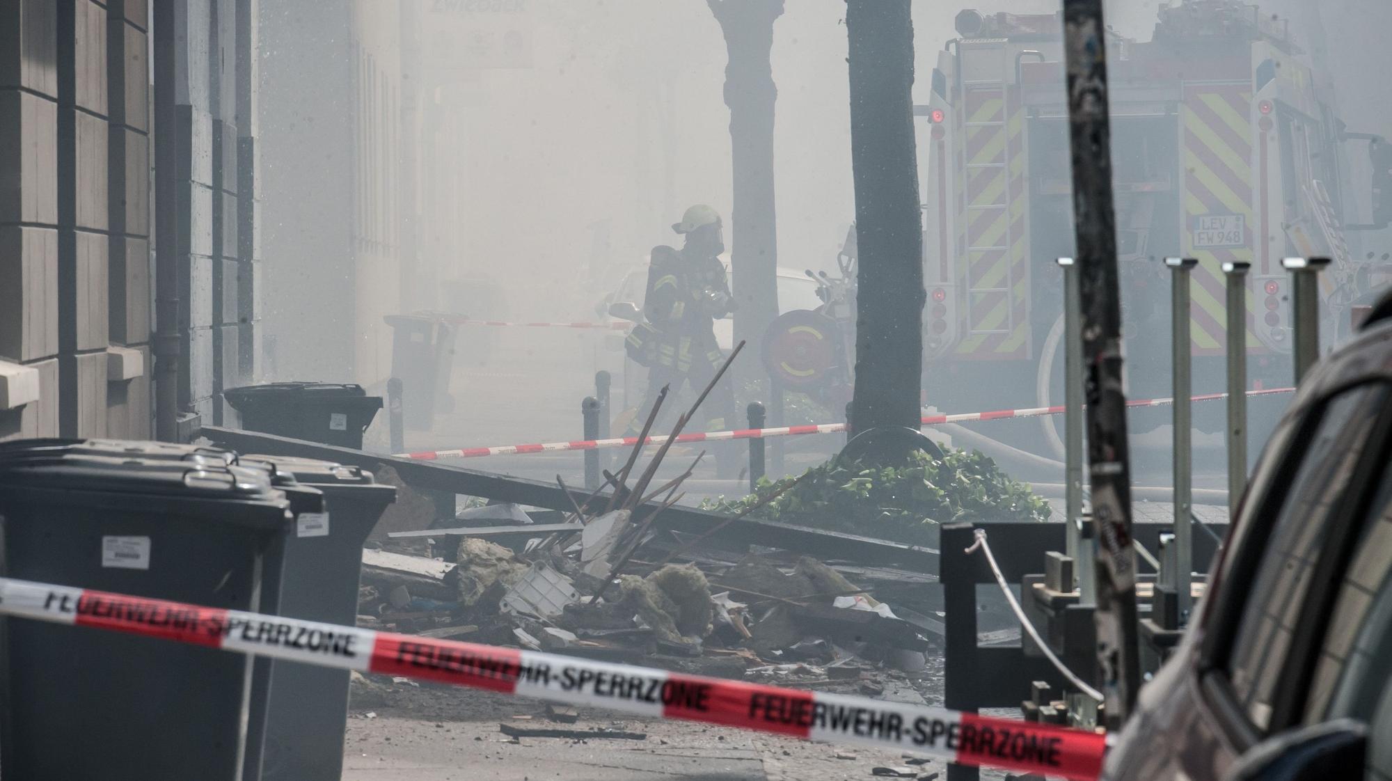 Trümmer liegen nach der Explosion auf der verrauchten Augustastraße in Opladen.