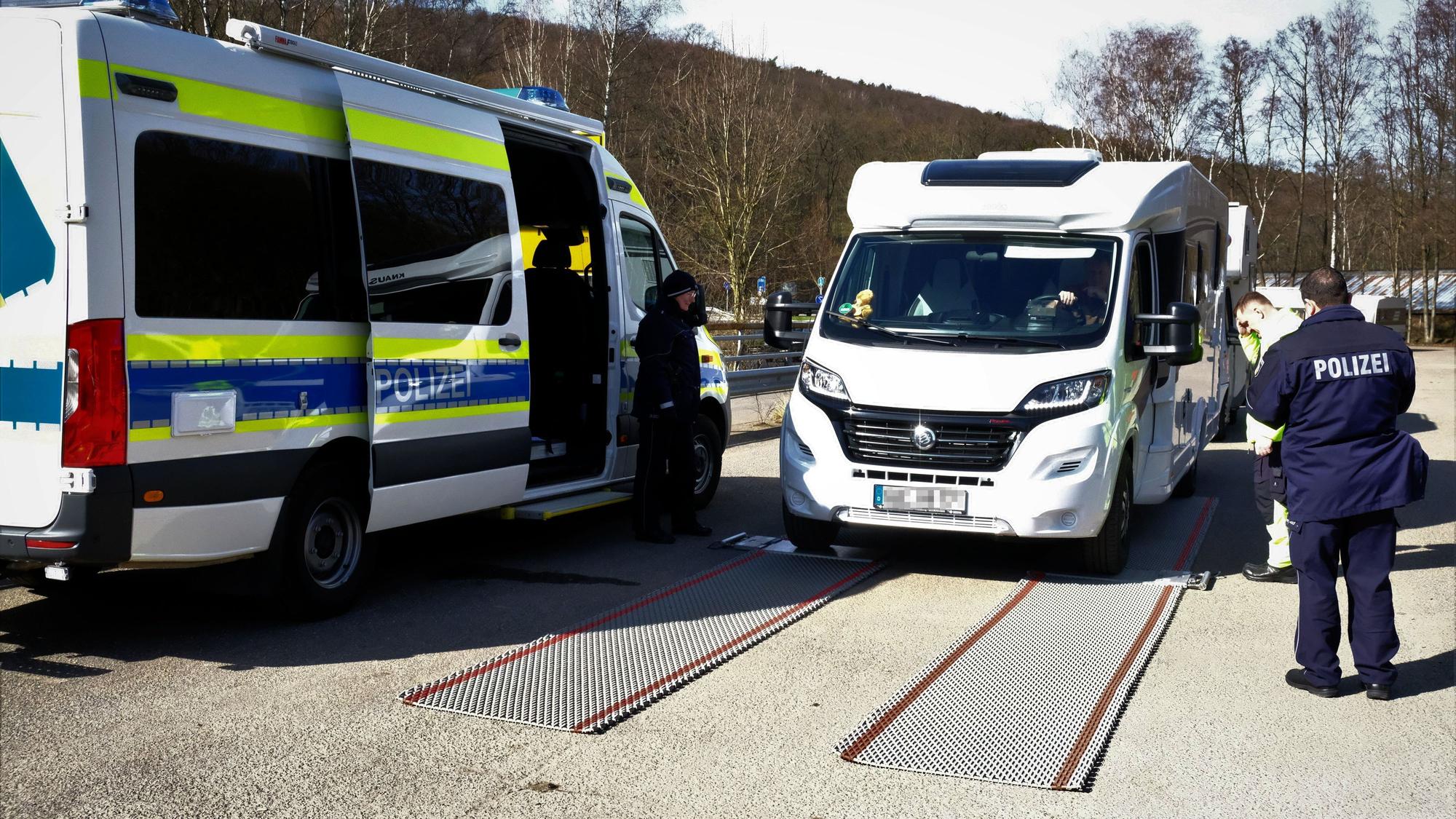 Ein Wohnmobil steht neben einem Polizeiwagen.