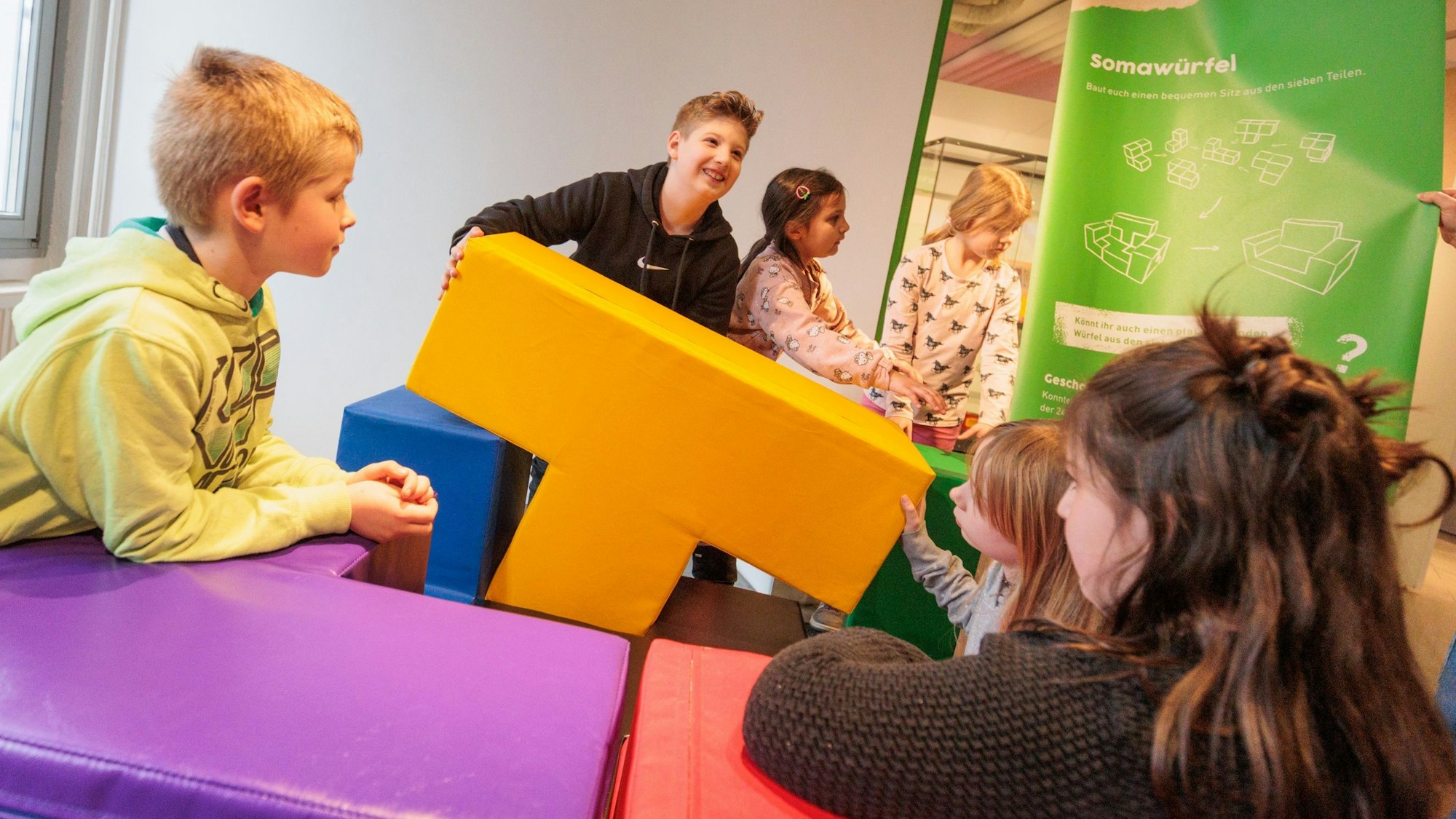 Mehrere Kinder spielen mit großen, weichen und bunten Bausteinen.