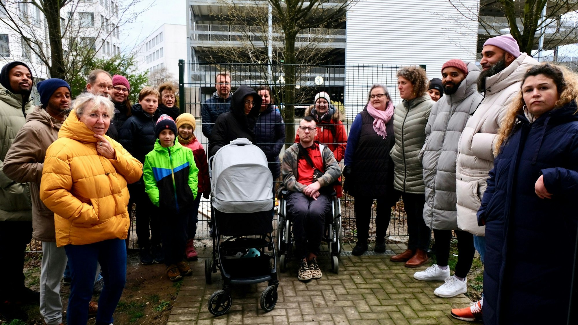 Menschen stehen an den beiden Seiten eines Zauns, der den Weg versperrt.