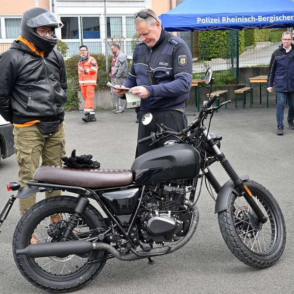 Die Polizei kontrolliert einen Zweiradfahrer.