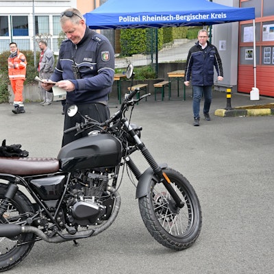 Die Polizei kontrolliert einen Zweiradfahrer.