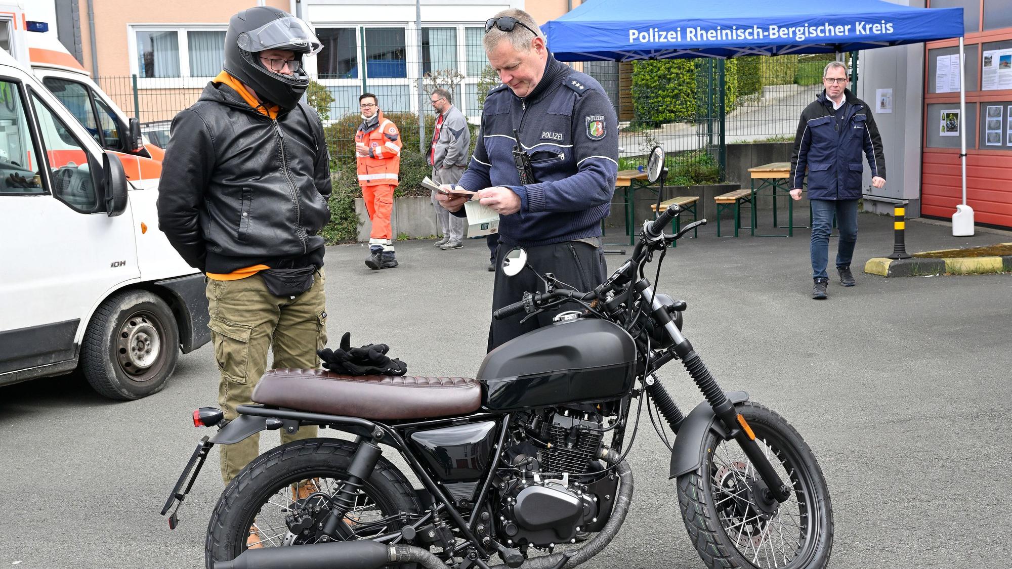 Die Polizei kontrolliert einen Zweiradfahrer.