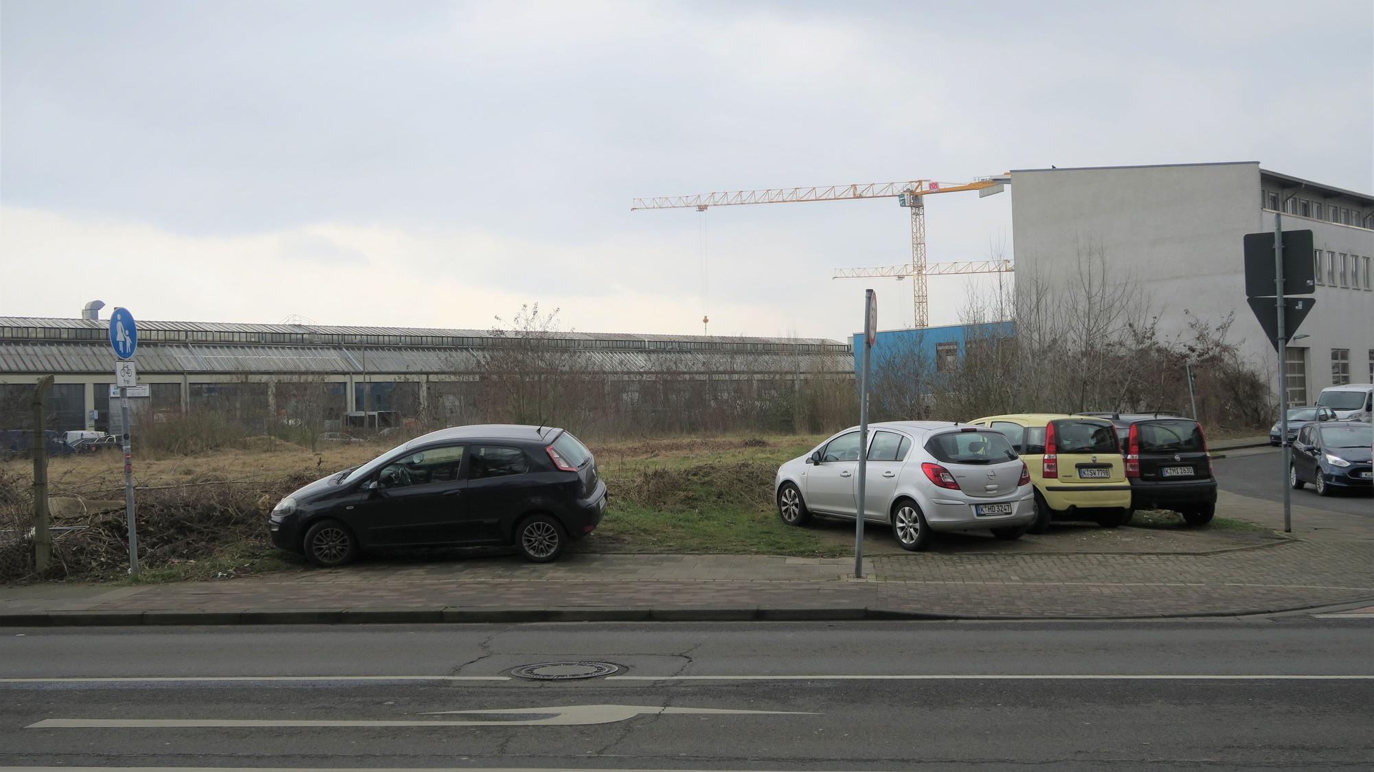 Eine Brachlandschaft liegt an einer Straße.