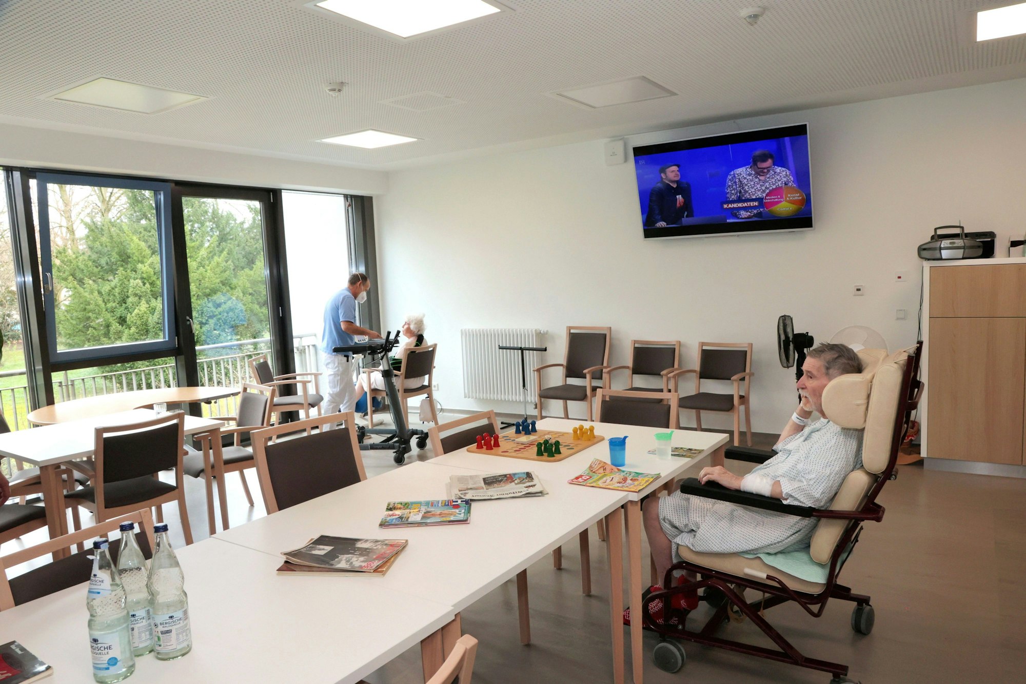Ein Mann sitzt in einem Aufenthaltsraum an einem Tisch und schaut zum Fenster hinaus.