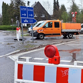 Eine rot-weiße Warnbake samt Durchfahrt-verboten-Schild versperrt die Zufahrt zur A4. Im Hintergrund ist ein Baufahrzeug zu sehen.