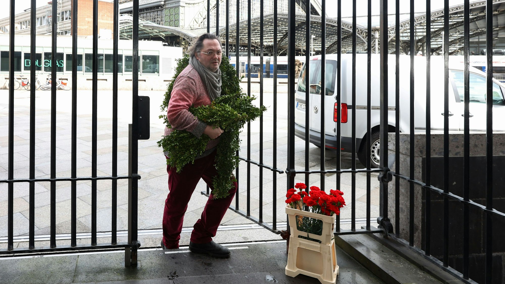 Mann bringt Buchsbaumzweige und rote Nelken in den Dom
