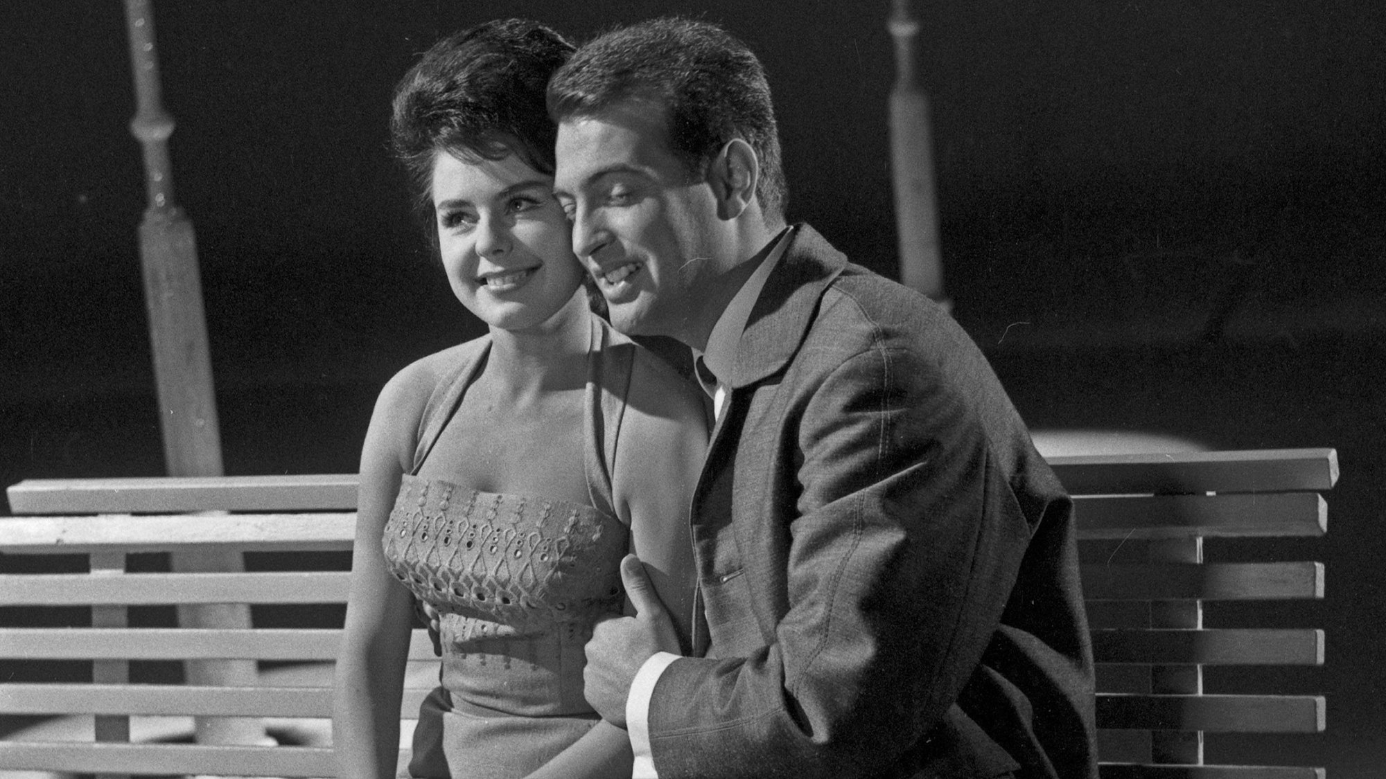 Wyn Hoop hält auf einer Bank Pirko Manola im Arm.