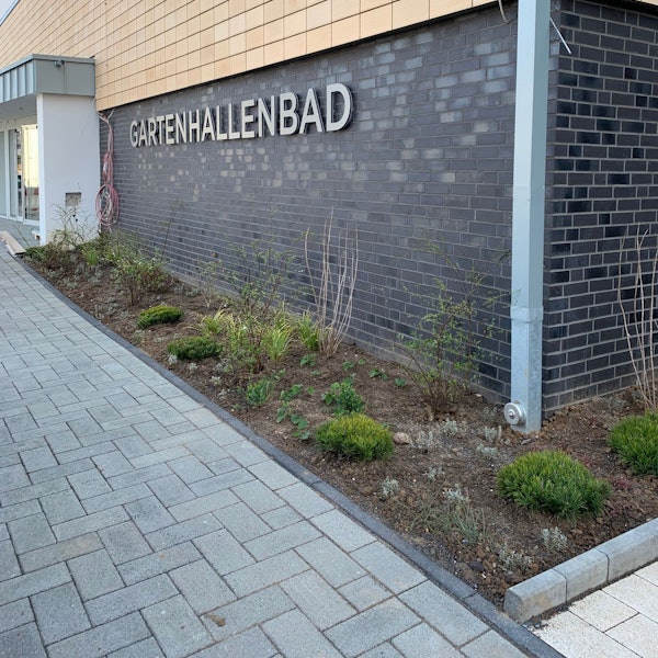 Das Bild zeigt das Gebäude des Schwimmbads von der Außenseite mit dem Schriftzug Gartenhallenbad.