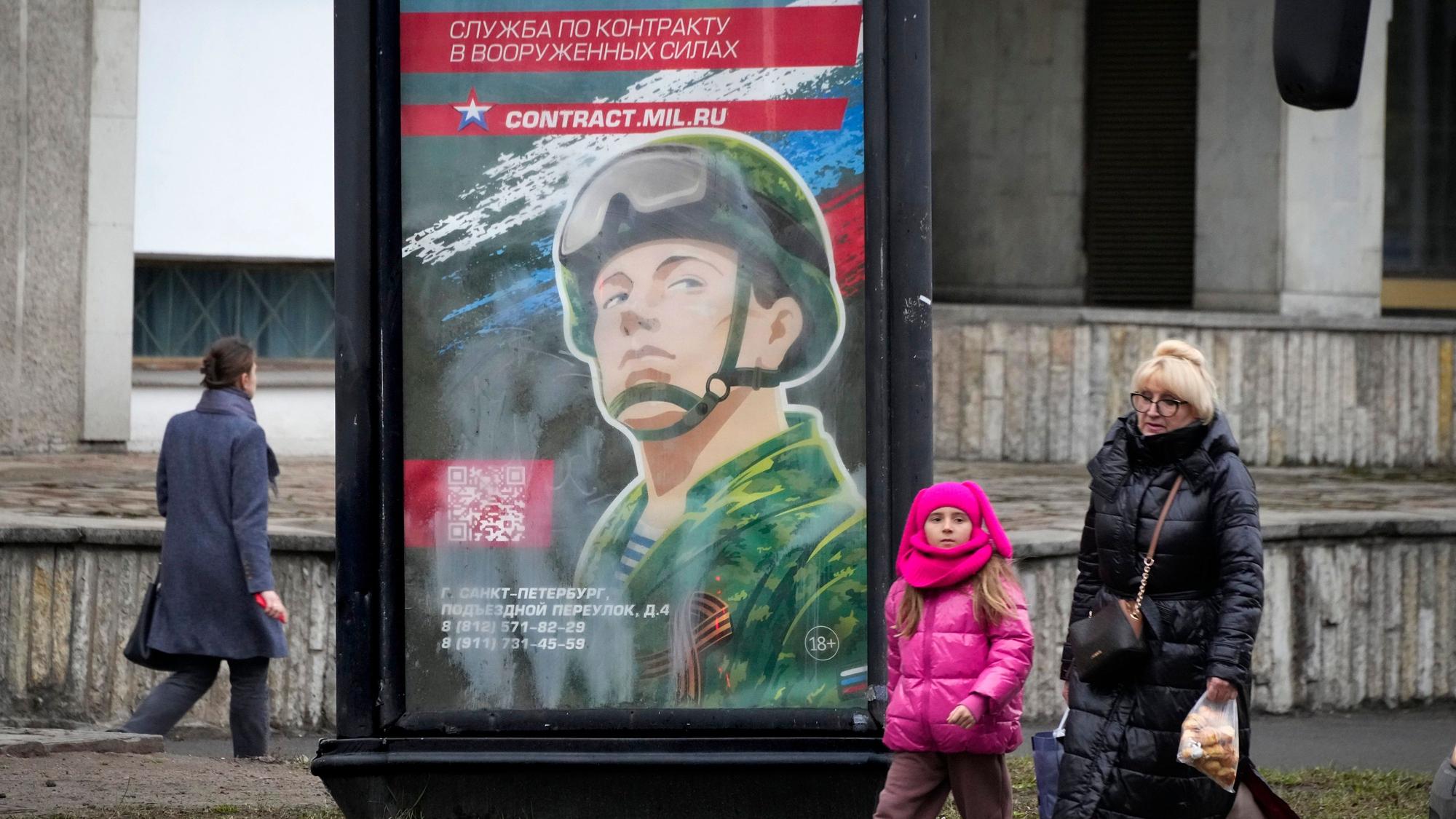 Menschen gehen an einem Rekrutierungsplakat der Armee mit der Aufschrift „Militärdienst unter Vertrag in den Streitkräften“ in Sakt Petersburg vorbei.