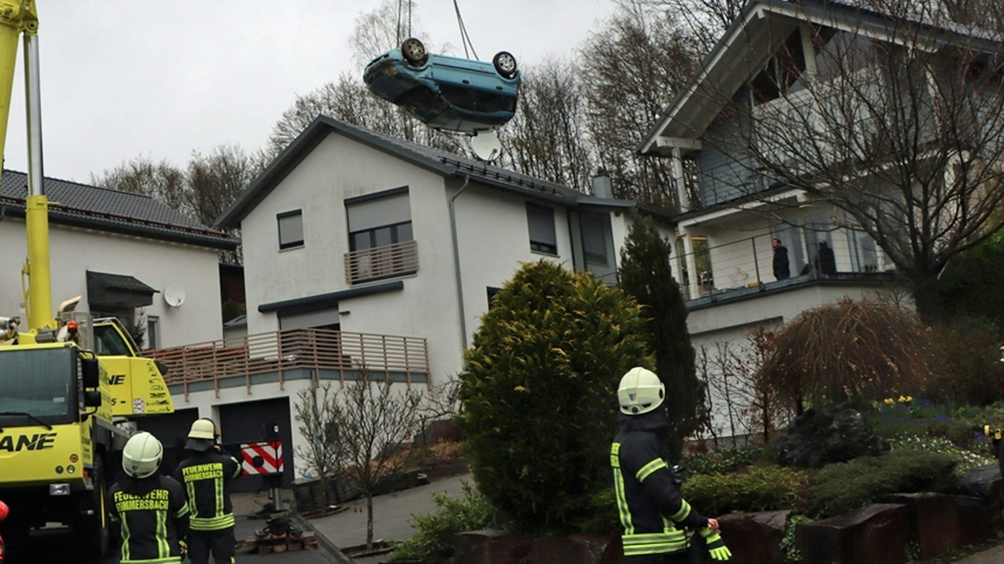 Ein blauer Kleinwagen hängt kopfüber an einem Kran.