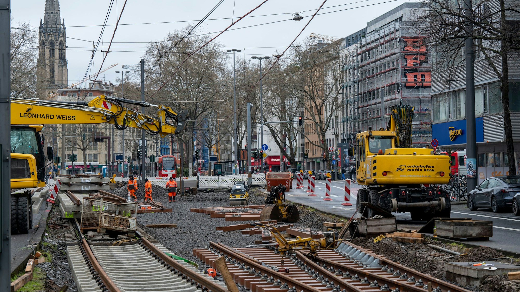In einem aufgerissenen Gleisbett liegen alte und neue Schienen, Baufahrzeuge stehen daneben.