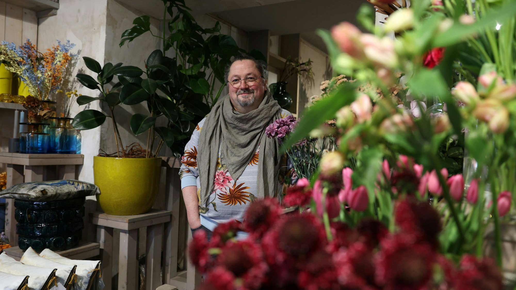 Mann inmitten einer Blütenpracht im Blumenladen