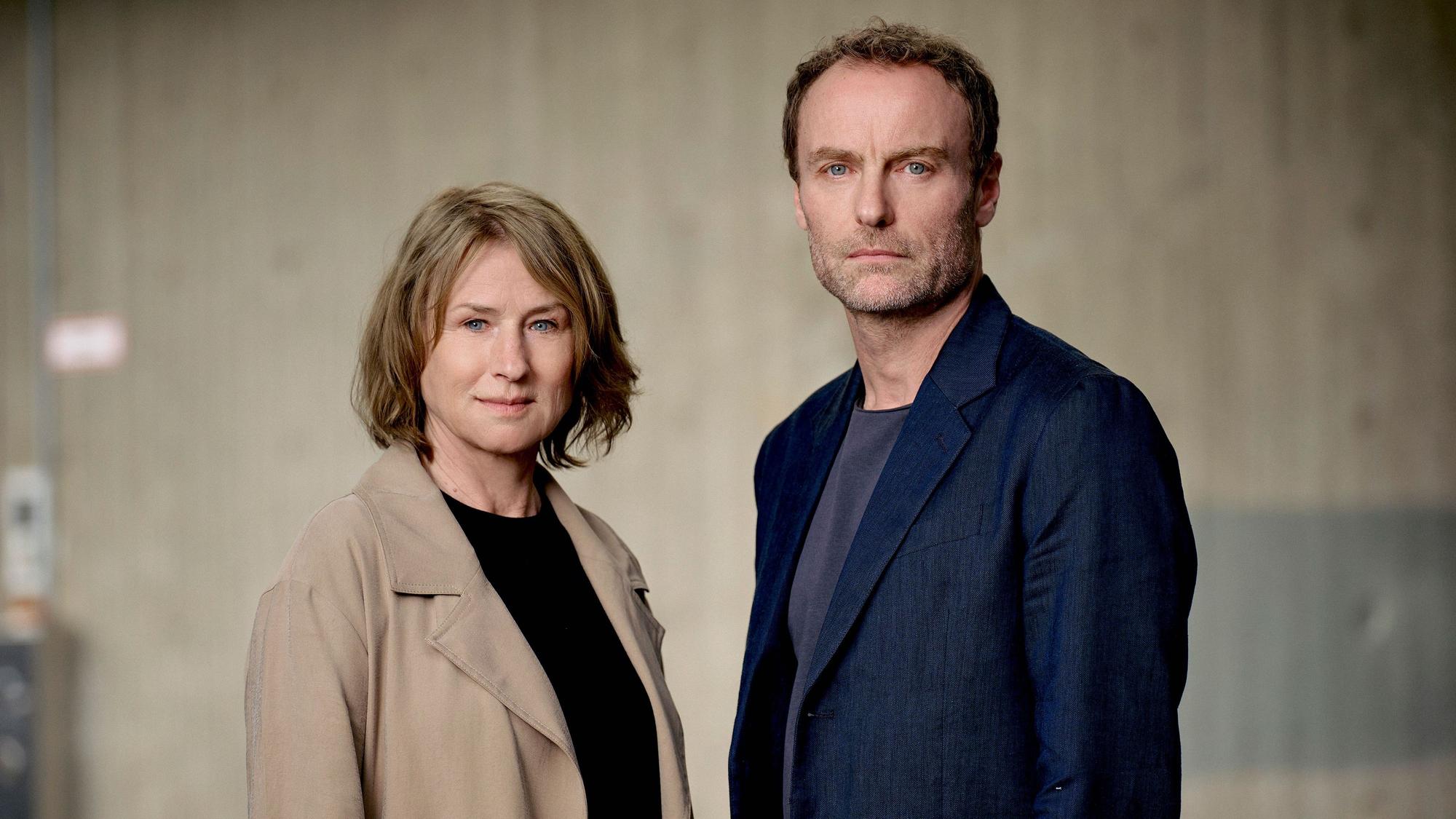 Corinna Harfouch und Mark Waschke stehen nebeneinander und schauen in die Kamera.