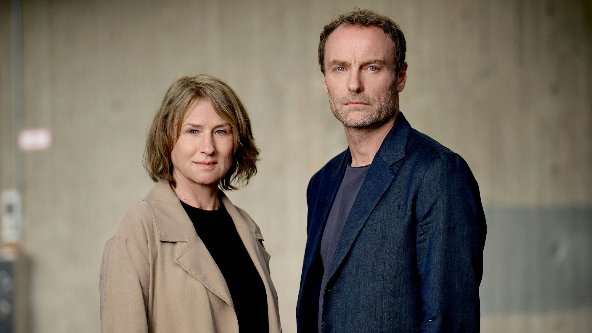 Corinna Harfouch und Mark Waschke stehen nebeneinander und schauen in die Kamera.