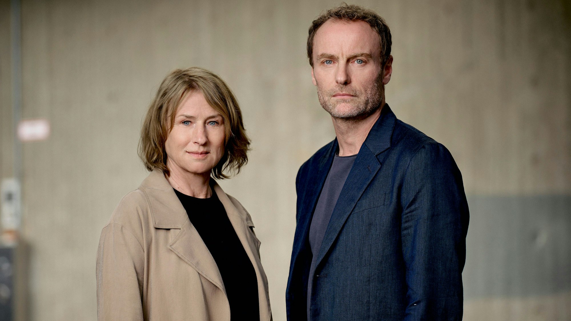 Corinna Harfouch und Mark Waschke stehen nebeneinander und schauen in die Kamera.