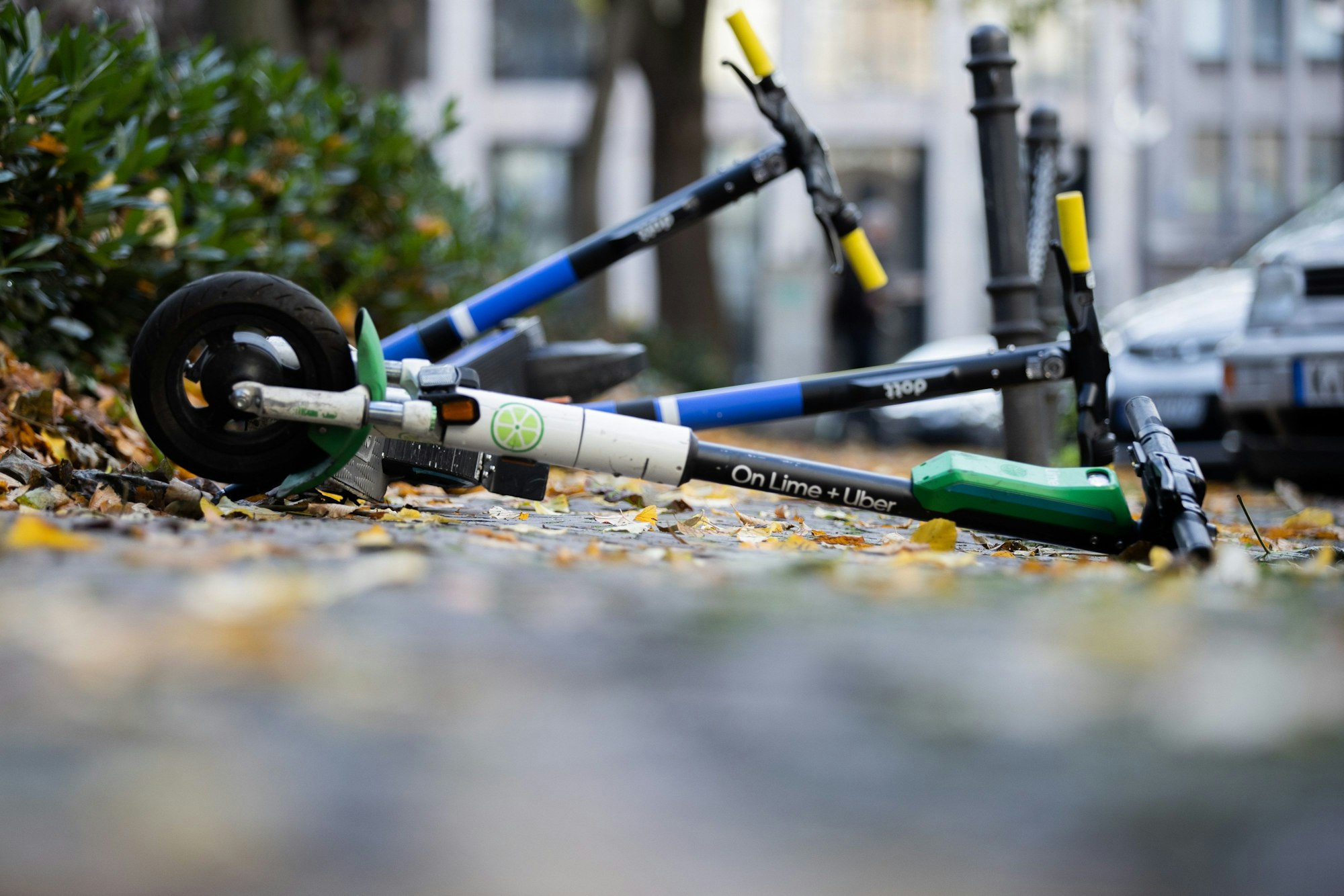 E-Scooter liegen auf einem Gehweg in Köln und versperren den Weg.