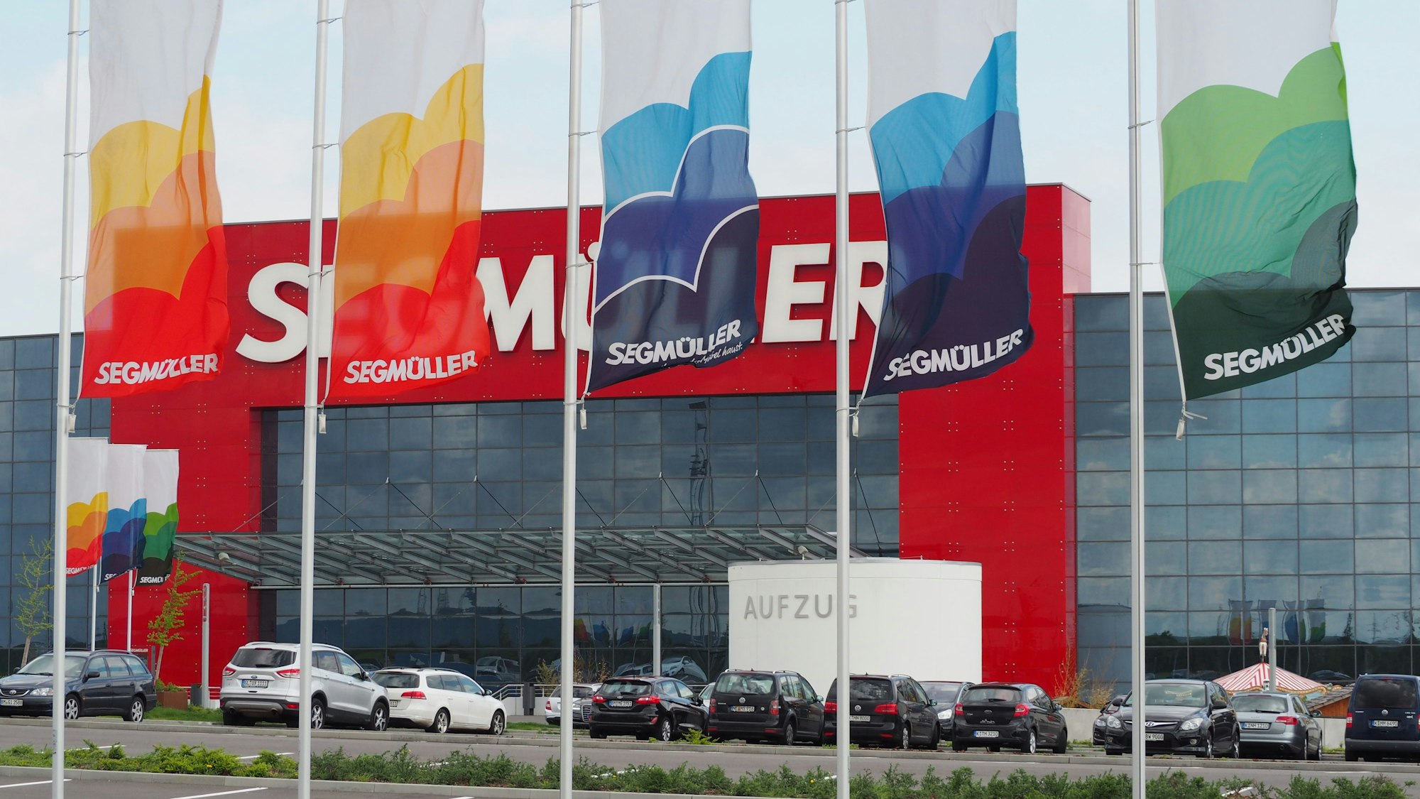 Im Vordergrund Fahnen, im Hintergrund die verglaste Fassade des Einrichtungshauses Segmüller.