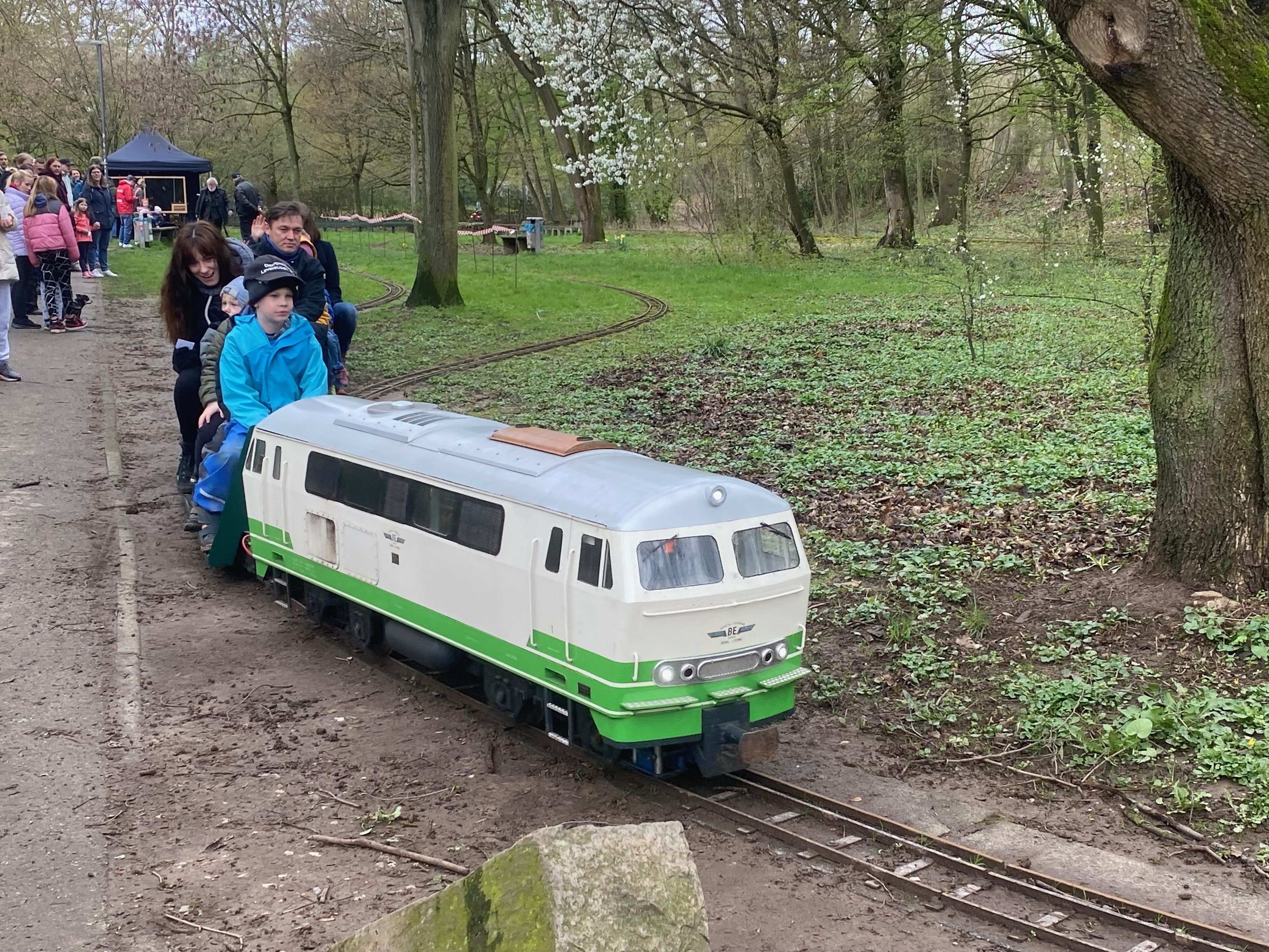 Dampfbahn-Lokomotive fährt mit Passagieren auf den Anhängern durch den Stadtpark