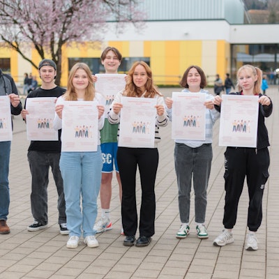 Zu sehen sind Menschen, die jeweils ein Plakat vor sich halten.